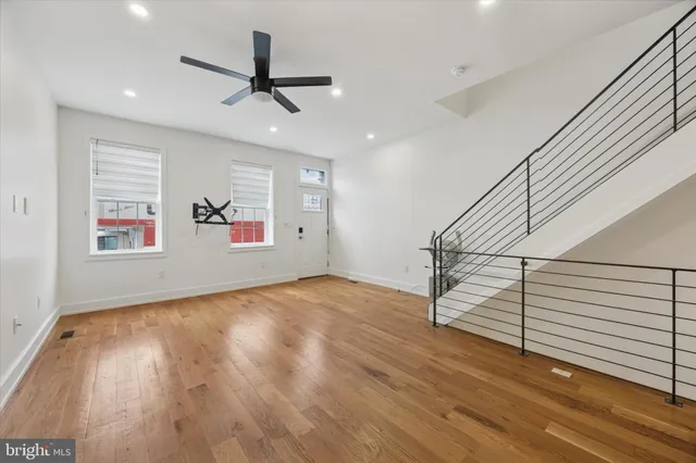 a view of empty room with wooden floor and fan