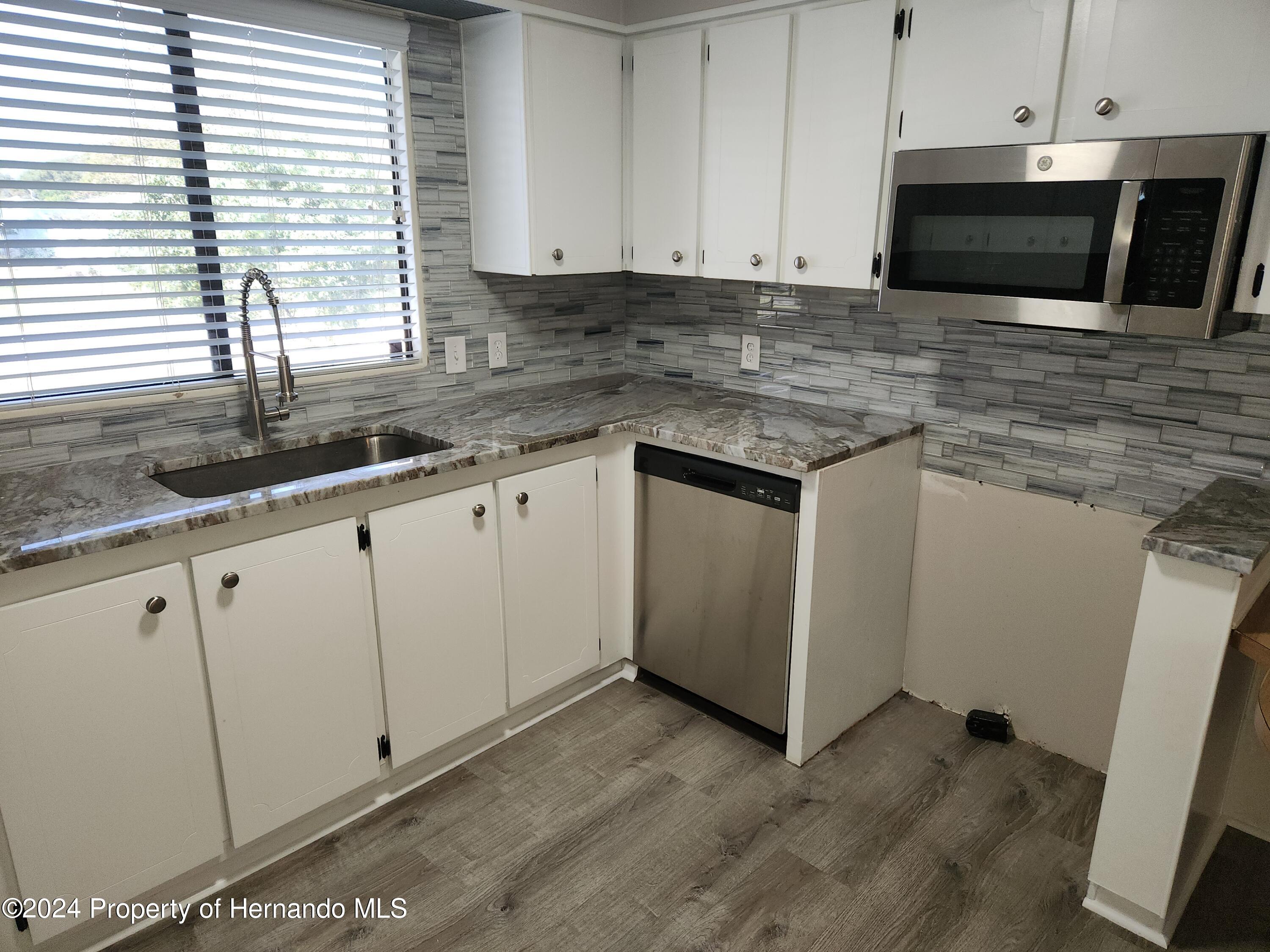 8040 Mission Street Brooksville, FL 34613 - Photo 3 of 17 a kitchen with granite countertop white cabinets and black stainless steel appliances