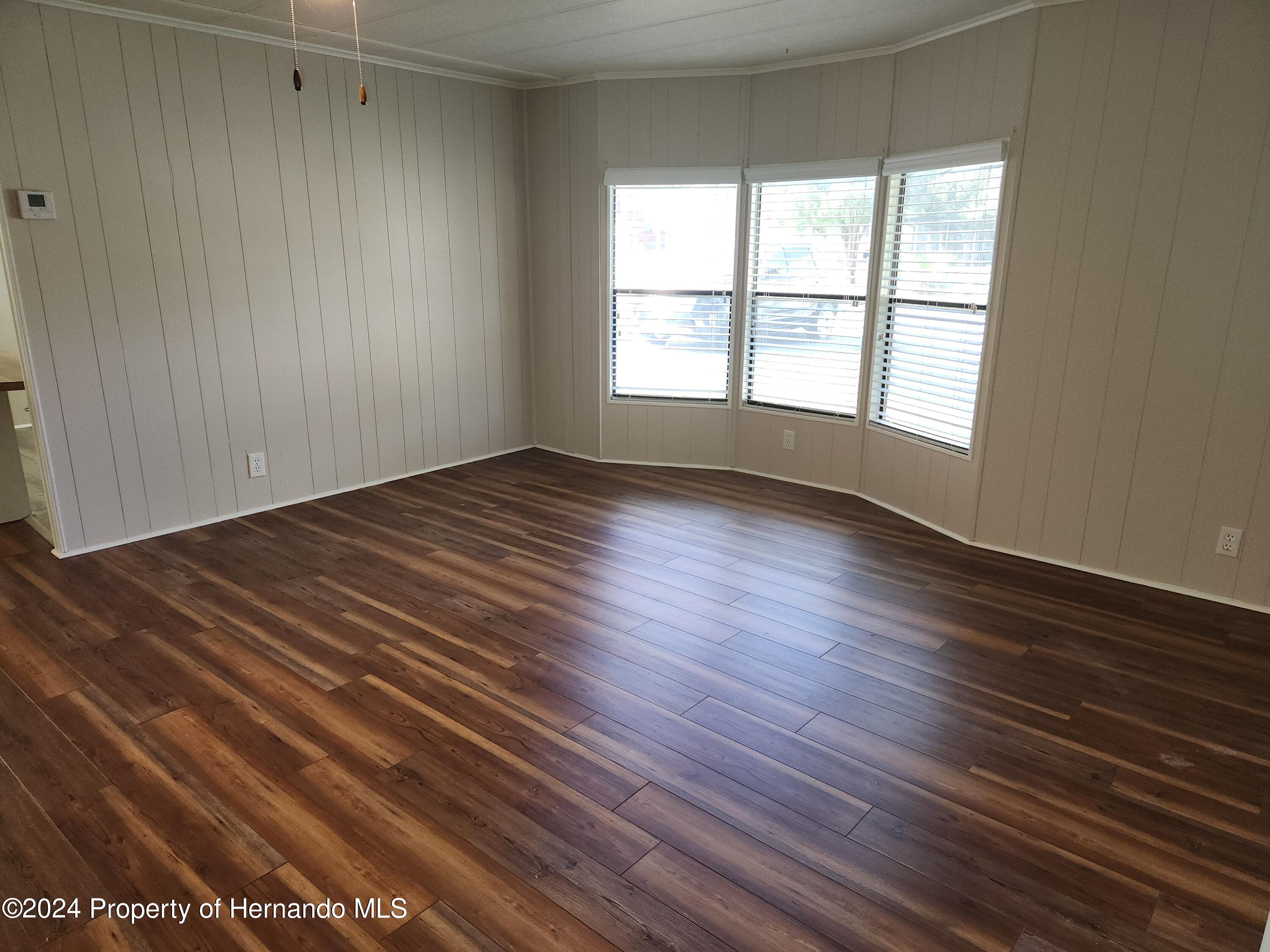8040 Mission Street Brooksville, FL 34613 - Photo 8 of 17 wooden floor in an empty room with a window