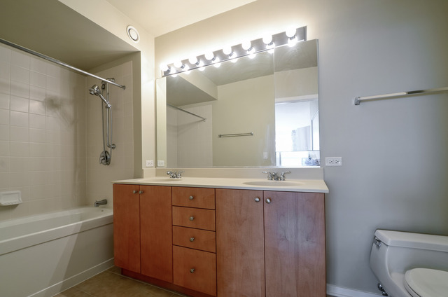 807 Davis Street, Unit 1405 Evanston, IL 60201 - Photo 9 of 12 a bathroom with a granite countertop sink a toilet a large mirror and shower