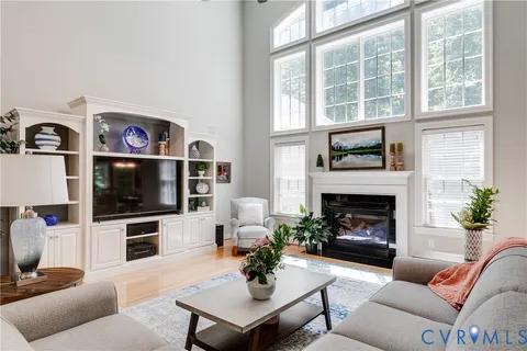 a living room with furniture a fireplace a flat screen tv and a large window
