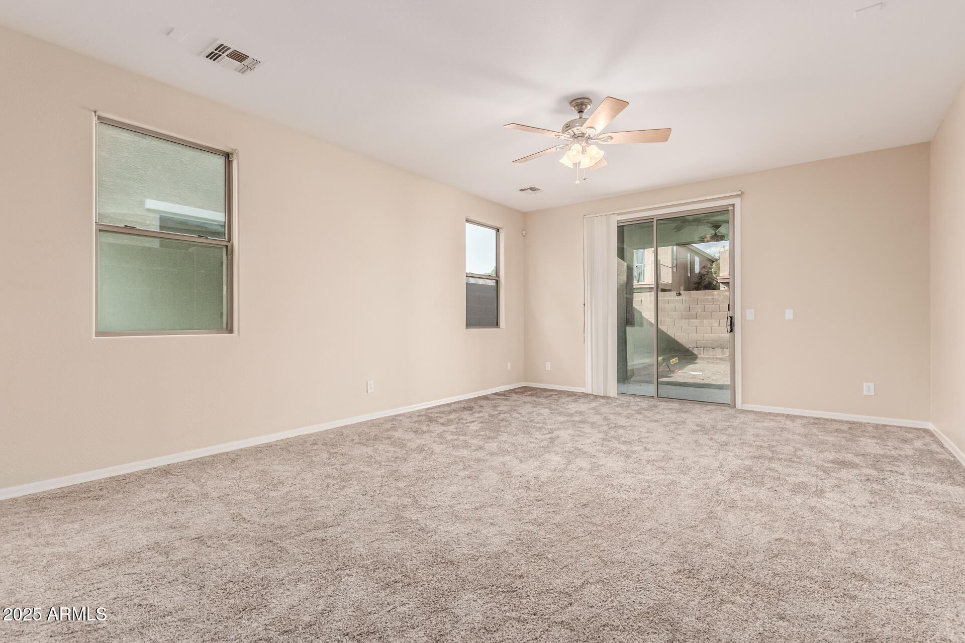 2530 West Gaby Road Phoenix, AZ 85041 - Photo 3 of 30 an empty room with chandelier fan and windows