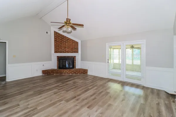 a view of empty room with fireplace and wooden floor
