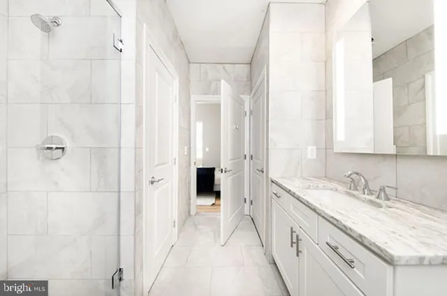 a bathroom with a granite countertop sink two mirror and a shower