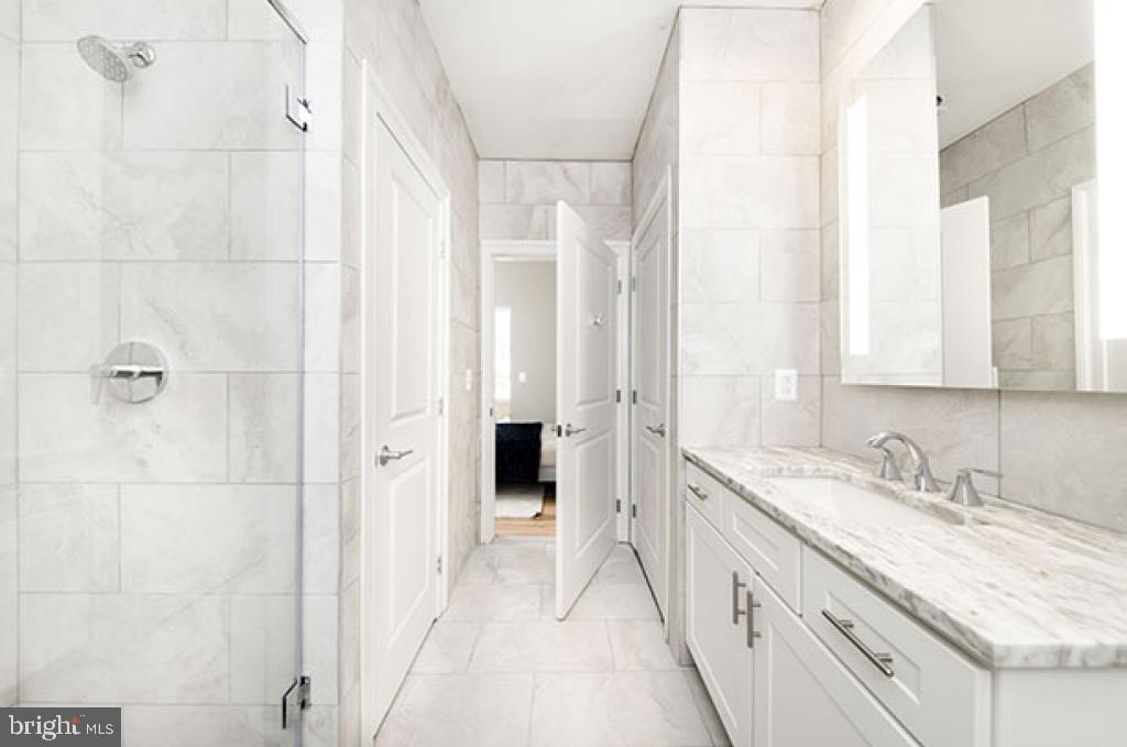 139-59 North 23rd Street, Unit 117 Philadelphia, PA 19103 - Photo 7 of 28 a bathroom with a granite countertop sink two mirror and a shower