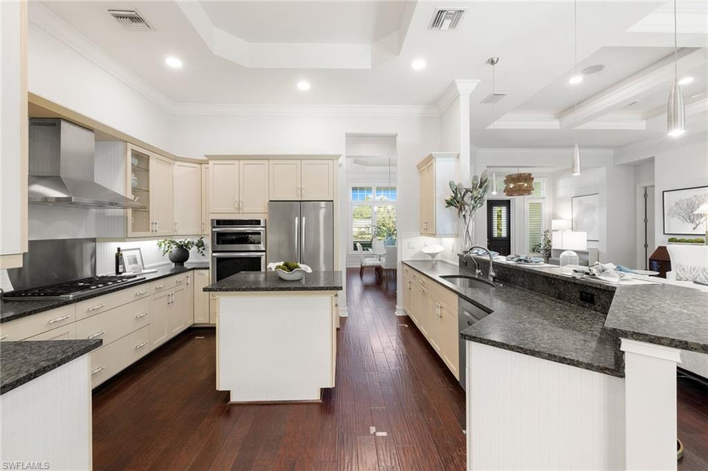 642 Bougainvillea Road Naples, FL 34102 - Photo 13 of 50 Kitchen featuring stainless steel appliances, wall chimney exhaust hood, cream cabinets, dark stone countertops, and recessed lighting