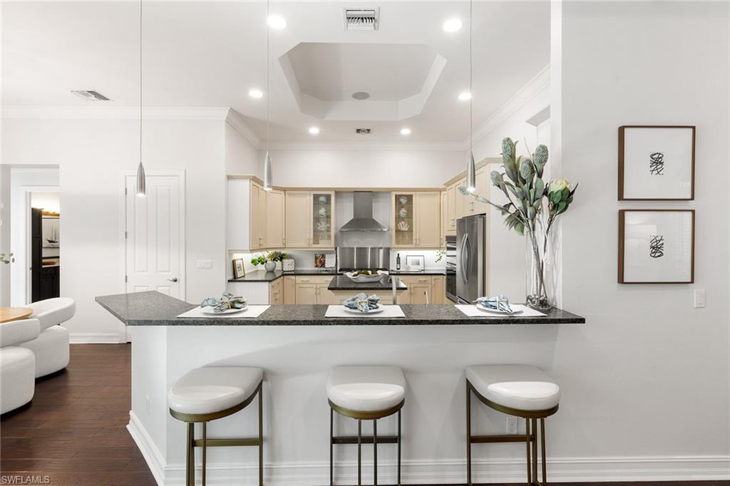 642 Bougainvillea Road Naples, FL 34102 - Photo 14 of 50 Kitchen featuring a peninsula, a kitchen bar, glass insert cabinets, pendant lighting, and appliances with stainless steel finishes