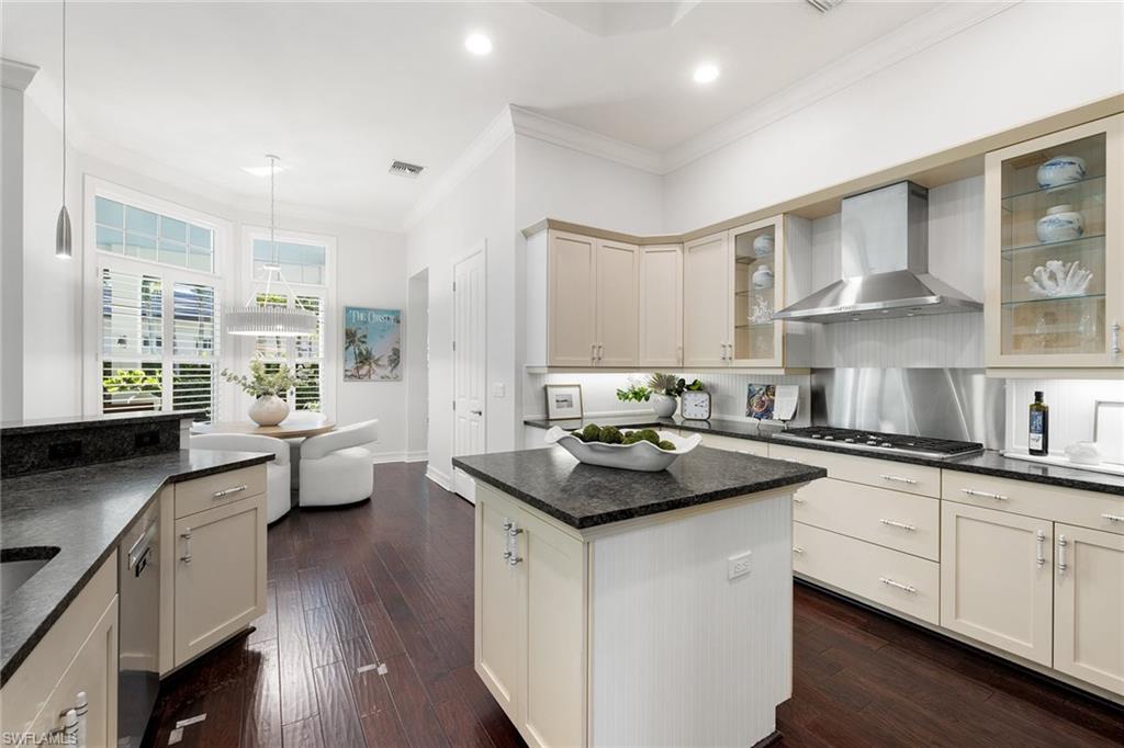 642 Bougainvillea Road Naples, FL 34102 - Photo 17 of 50 Kitchen featuring ornamental molding, wall chimney exhaust hood, pendant lighting, a kitchen island, and dark wood finished floors