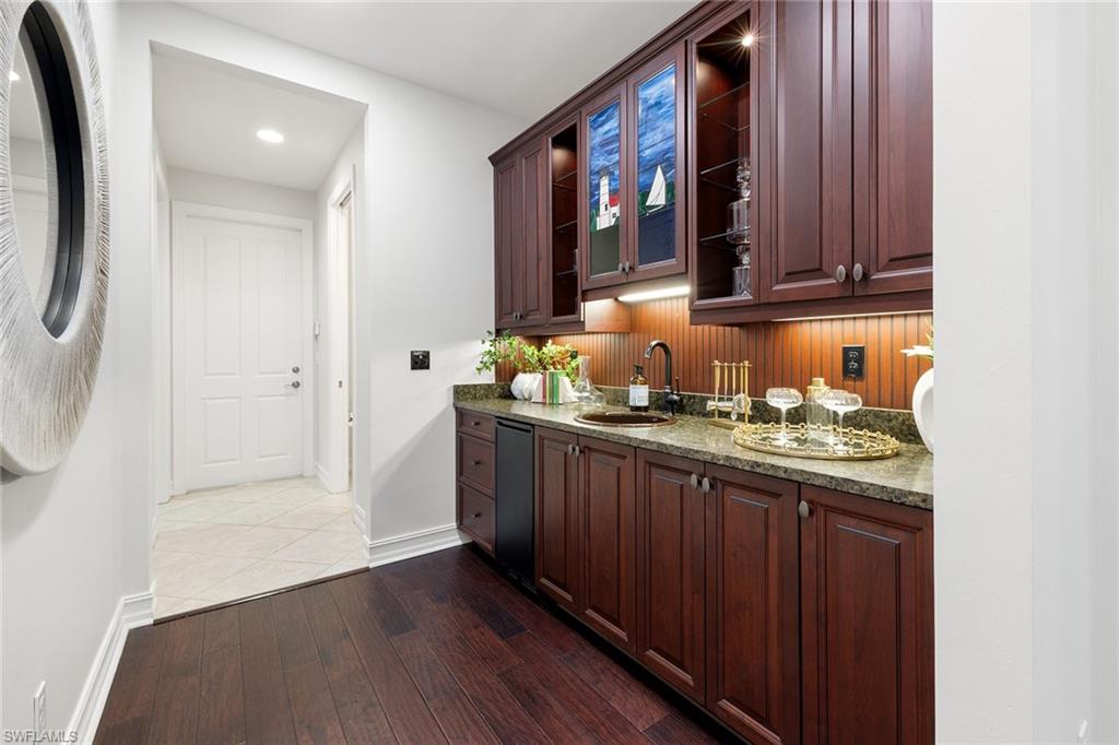 642 Bougainvillea Road Naples, FL 34102 - Photo 37 of 50 Bar area featuring glass insert cabinets, dark wood-style flooring, dark brown cabinets, dark stone counters, and recessed lighting