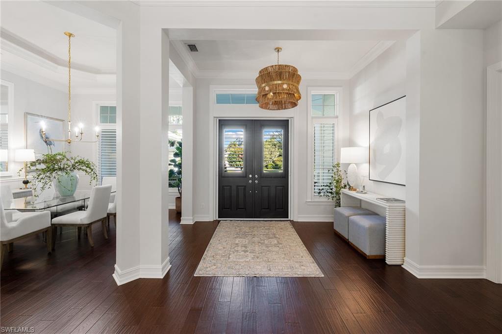642 Bougainvillea Road Naples, FL 34102 - Photo 4 of 50 Foyer entrance with a chandelier, crown molding, and dark wood finished floors