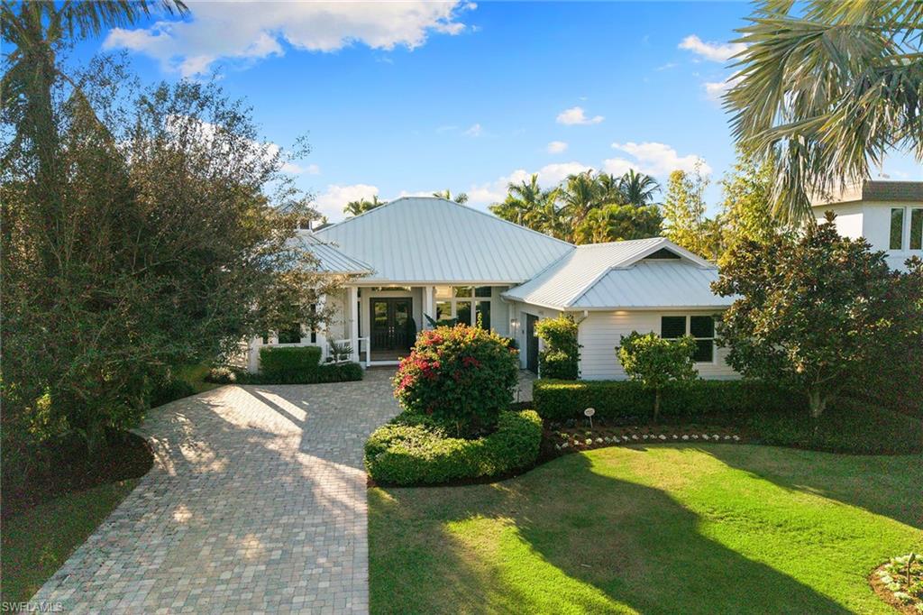 642 Bougainvillea Road Naples, FL 34102 - Photo 48 of 50 View of front of property with a porch, decorative driveway, a front yard, and a metal roof