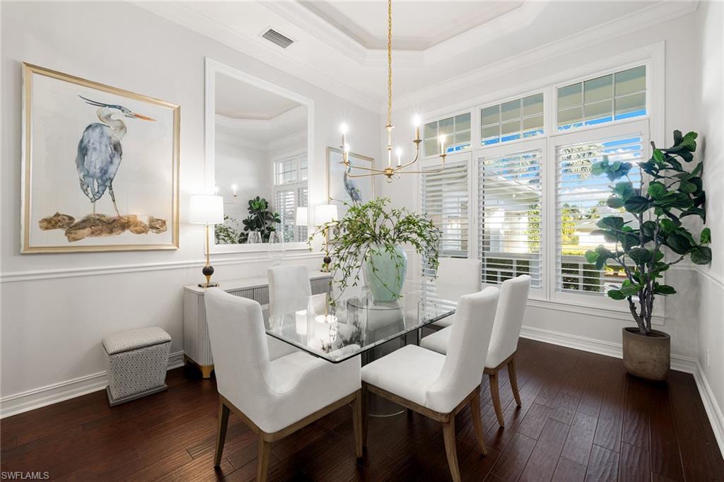 642 Bougainvillea Road Naples, FL 34102 - Photo 5 of 50 Dining area with ornamental molding, a raised ceiling, dark wood finished floors, and a chandelier