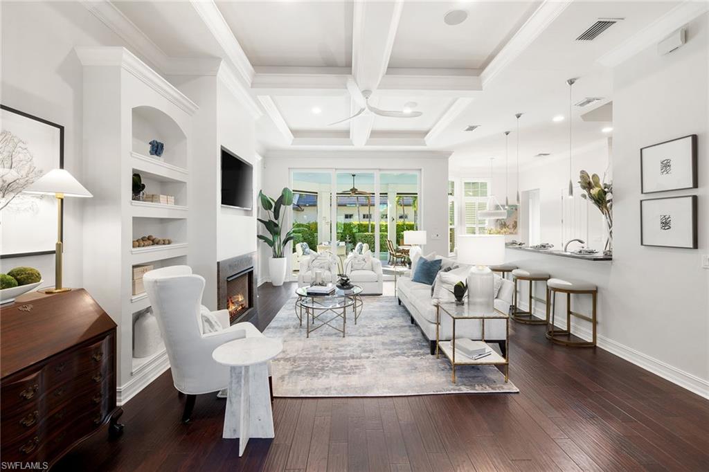 642 Bougainvillea Road Naples, FL 34102 - Photo 6 of 50 Living room with dark wood-type flooring, a lit fireplace, beam ceiling, coffered ceiling, and built in shelves