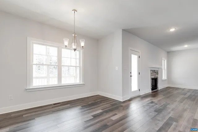 an empty room with wooden floor cabinet and windows