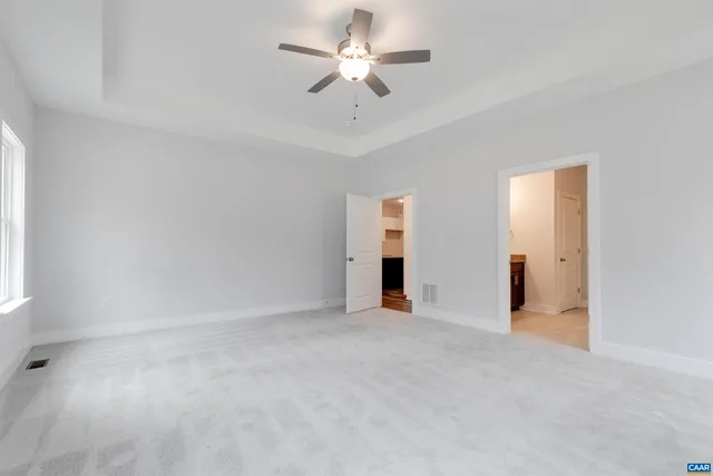 an empty room with chandelier fan and windows
