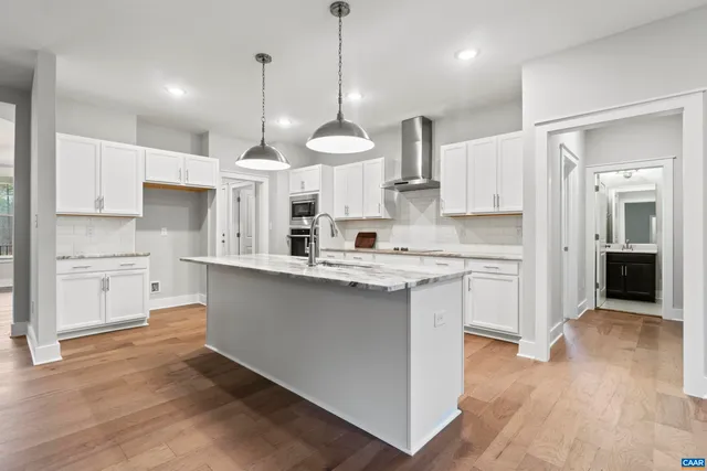 a kitchen with stainless steel appliances granite countertop a stove a sink dishwasher a refrigerator and white cabinets with wooden floor