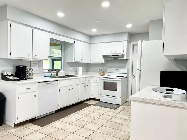 a kitchen with granite countertop white cabinets and white appliances