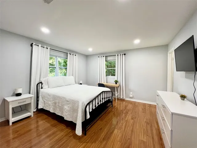 a spacious bedroom with a bed and a flat screen tv