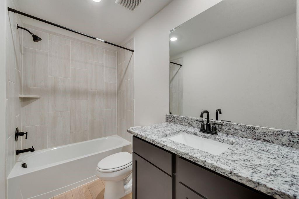 1421 Butler Avenue Princeton, TX 75407 - Photo 15 of 25 a bathroom with a granite countertop sink a toilet a mirror a shower and bathtub