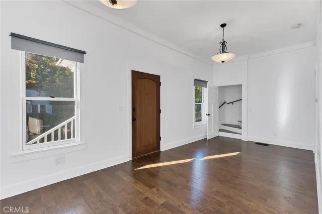 a view of an empty room with a window and wooden floor