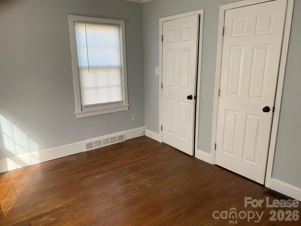 an empty room with wooden floor and closet area