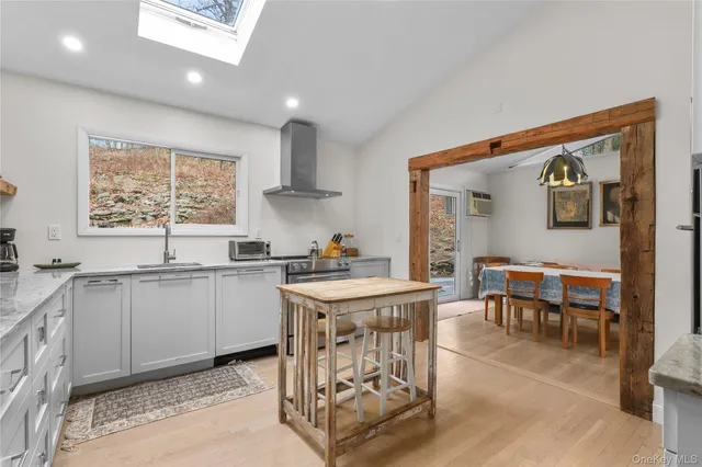 a kitchen with stainless steel appliances granite countertop a stove top oven a sink a dining table and chairs with the wooden floor