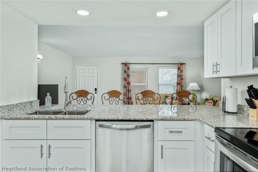 3607 Edgewater Drive Sebring, FL 33872 - Photo 6 of 22 a kitchen with granite countertop white cabinets and white appliances