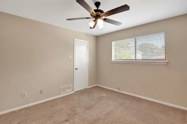 an empty room with a window and a fan