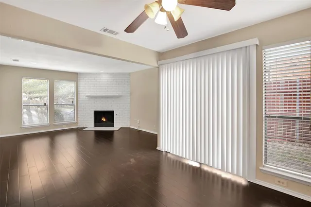 an empty room with wooden floor fireplace and windows