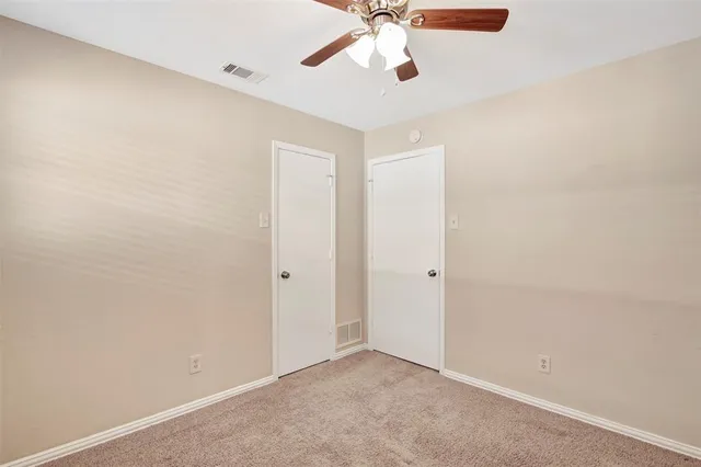 an empty room with a window and a fan