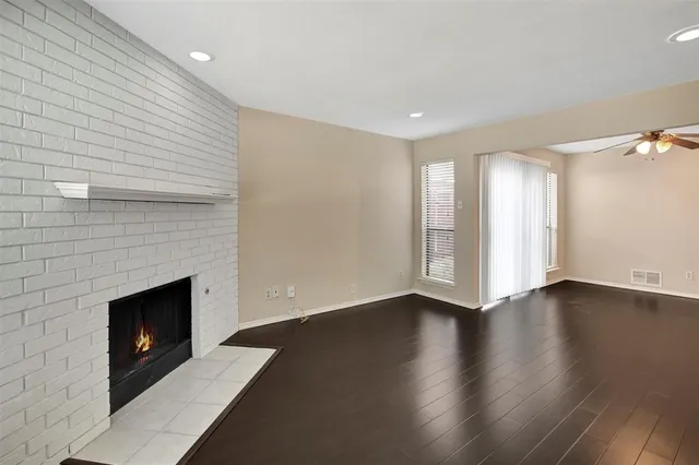 an empty room with wooden floor fireplace and windows