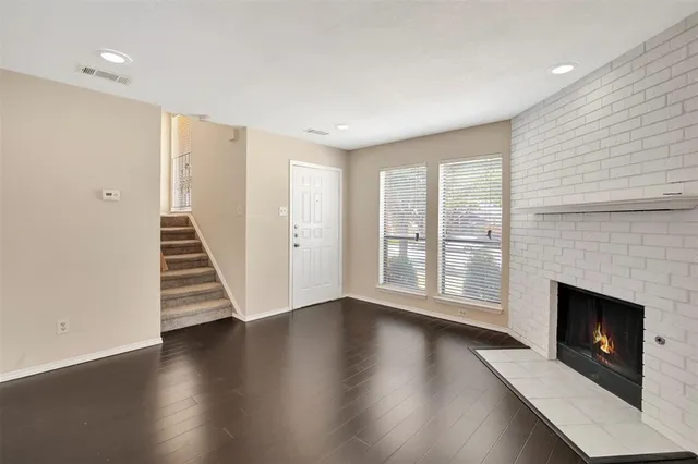 an empty room with wooden floor fireplace and windows