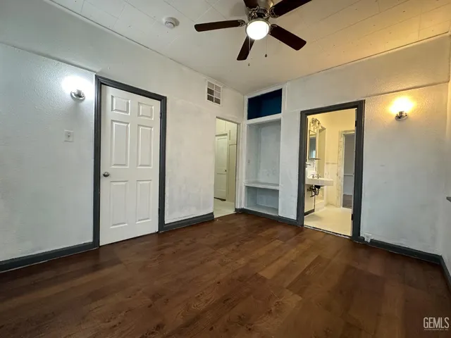 an empty room with wooden floor fan and windows