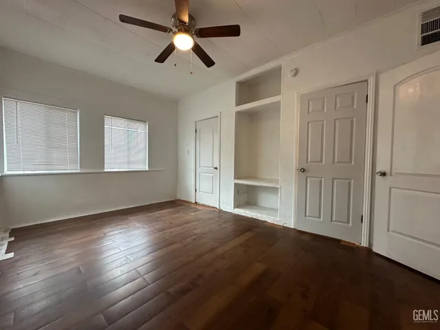 a view of empty room with wooden floor and fan