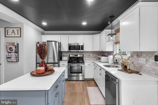 a kitchen with stainless steel appliances a sink dishwasher stove refrigerator and cabinets