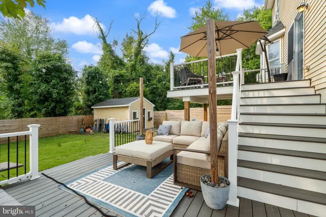 a view of a patio with couches table and chairs under an umbrella with a garden