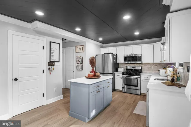 a kitchen with stainless steel appliances a stove refrigerator and cabinets