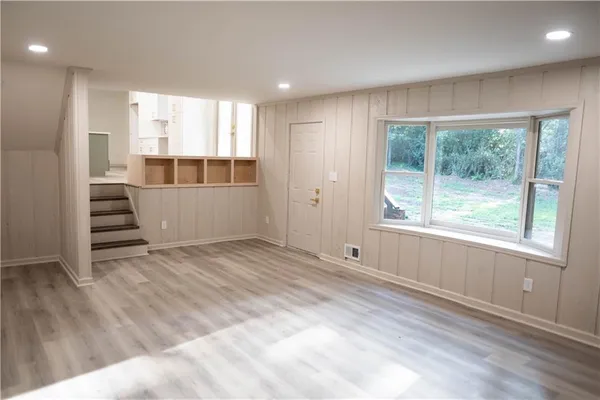 a view of an empty room with wooden floor and a window
