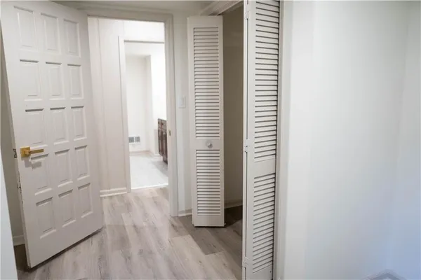 a view of a hallway with wooden floor and closet