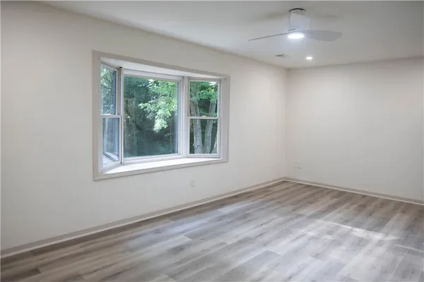 an empty room with wooden floor and windows