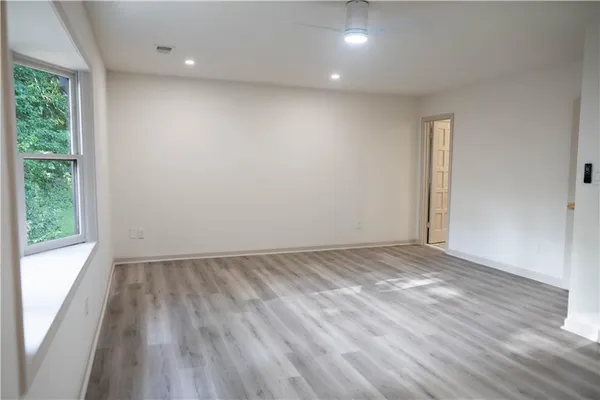 an empty room with wooden floor and windows