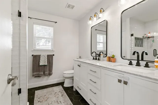 a bathroom with 2 sink toilet and a mirror