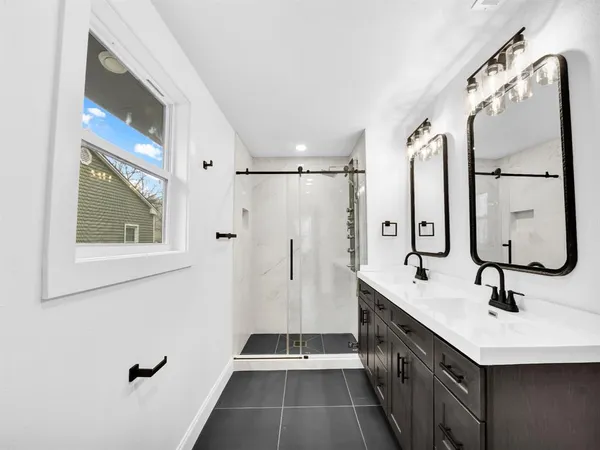 a bathroom with a double vanity sink a large mirror and shower