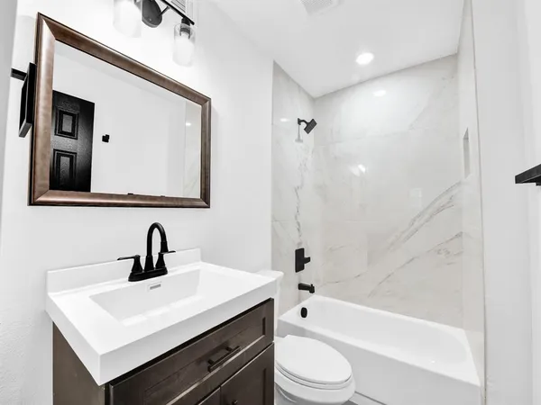 a bathroom with a sink a toilet a mirror and bathtub