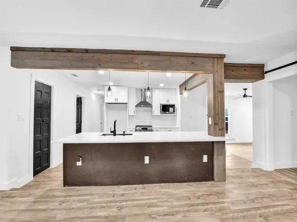 a view with cabinets a sink dishwasher and a fireplace with wooden floor