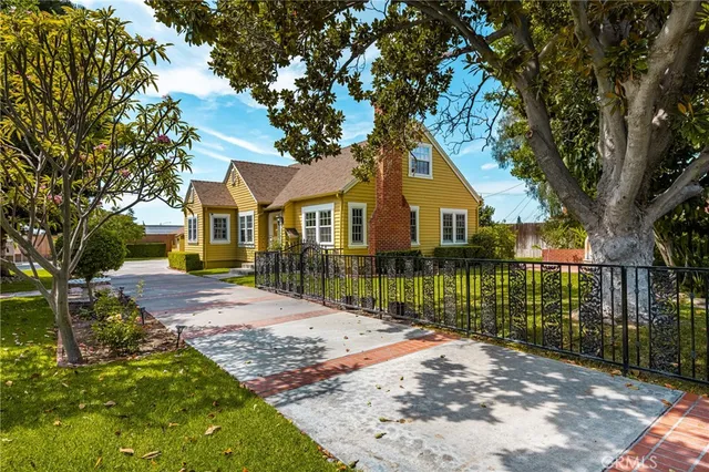 a view of a house with a small yard plants and a large tree