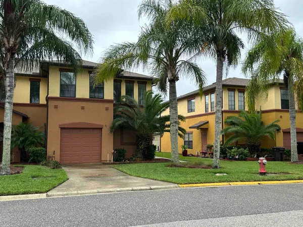 a front view of a house with a garden and palm trees