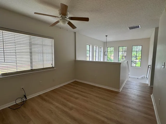 a view of an empty room with a window and wooden floor