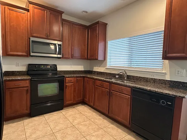 a kitchen with granite countertop wooden cabinets stainless steel appliances and a sink