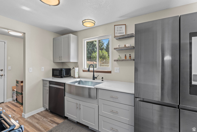 564 Swenson Avenue Springville, UT 84663 - Photo 8 of 26 Modern kitchen with wood-finish flooring, light gray cabinetry, stainless steel farmhouse sink, and a black faucet
